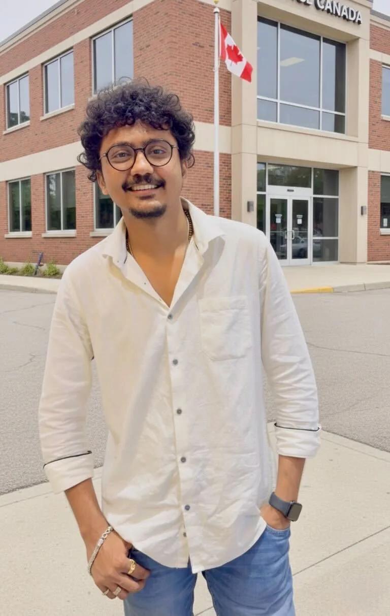 Ronak smiling near a Canadian flag